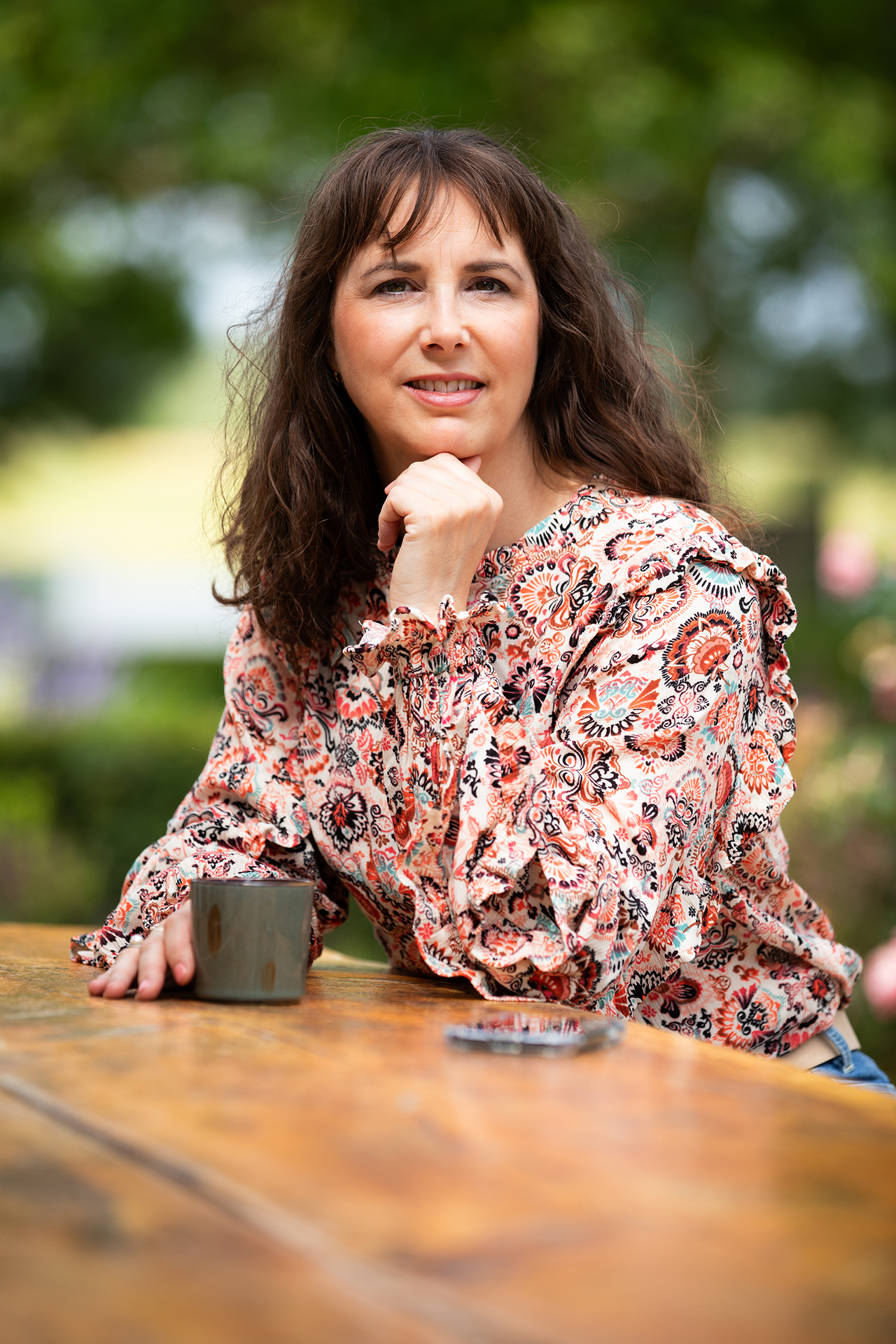 vrouw zittend aan tafel met kop koffie